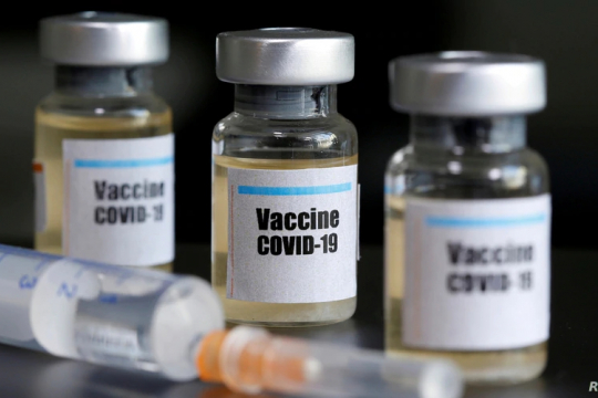 Small bottles labeled with a "Vaccine COVID-19" sticker and a medical syringe