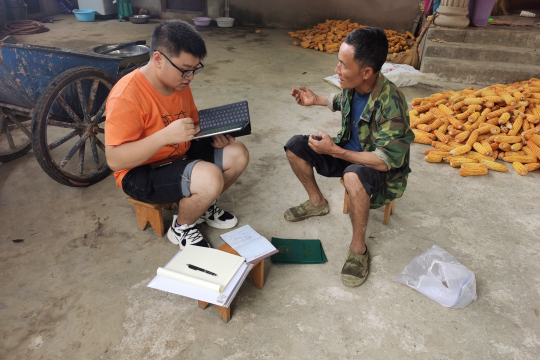 A farmer answering questions attentively, with his Hukou and Forest Rights Certificates showed to the interviewer