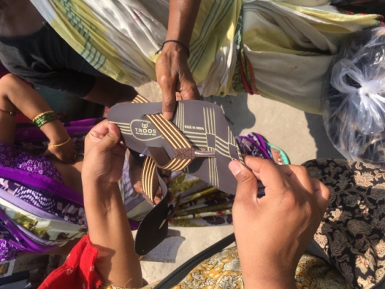 Home based worker in Udyog Nagar slum attaching strap to slipper