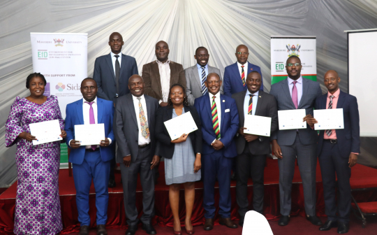 Minister Okasai (3rd) and Barnabas Nawangwe ( in a group photo with the graduands (5th)