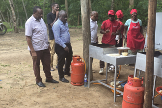 Dr. Rugaimukamu observing Matima Investment Group demonstrating the preparation of chapati using a modified gas cooker as a clean and efficient alternative to traditional charcoal cookers.